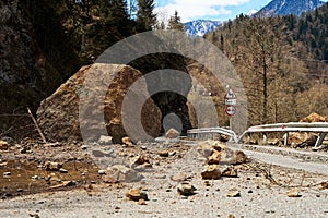 A huge rock fell from the mountains onto the road, destroying the asphalt and blocking half of the roadway