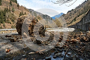 A huge rock fell from the mountains onto the road, destroying the asphalt and blocking half of the roadway