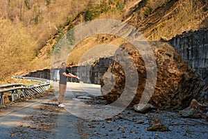 A huge rock fell from the mountains onto the road, destroying the asphalt and blocking half of the roadway