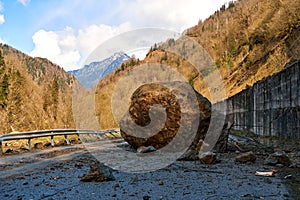 A huge rock fell from the mountains onto the road, destroying the asphalt and blocking half of the roadway