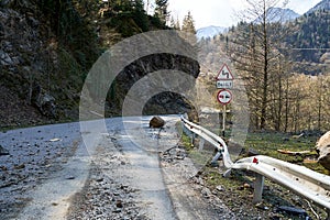 A huge rock fell from the mountains onto the road, destroying the asphalt and blocking half of the roadway