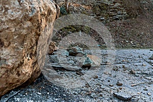 A huge rock fell from the mountains onto the road, destroying the asphalt and blocking half of the roadway