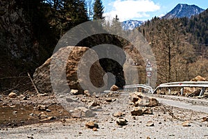 A huge rock fell from the mountains onto the road, destroying the asphalt and blocking half of the roadway