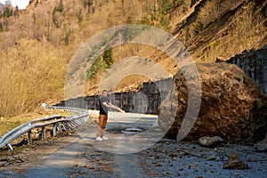 A huge rock fell from the mountains onto the road, destroying the asphalt and blocking half of the roadway