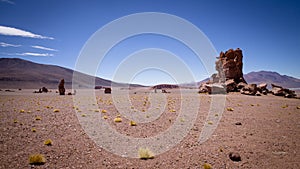 Huge rocks rise up on a flat plain of red sand in the Atacama Desert, the so-called Monjes de Pacana.