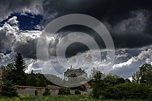 Huge scary ancient creepy castle on the top of the hill under dark cloudy sky