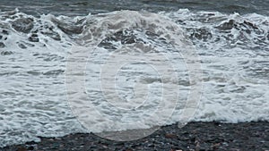 Huge sea waves of dirty water crashes powerfully on the shore in storm in slow motion