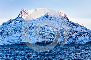 Huge Sermitsiaq mountain covered in snow with blue sea and small