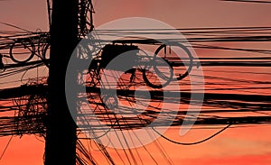 Huge and several electric and communication wires and cords hang on pole with disorganized and confused in colorful evening sky