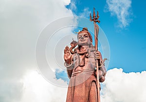 Huge Shiva statue Mangal Mahadev is a 33 m art piece in Ganga talao temple on the blue cloudy sky, Mauritius island