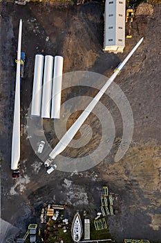 Huge size wind turbine blade on a platform ready for transportation in a yard. Aerial view. Heavy and long cargo movement.