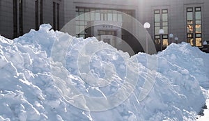 Huge snowdrifts under bright winter sun near the entrance to a library with a message of entrance in Russian