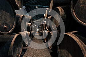 Huge spase with wooden barrels full of port wine inside traditional winery. Dark cellar for winemaking, Portugal