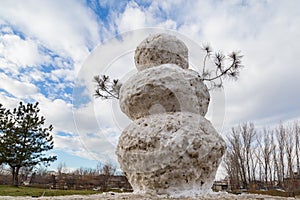 Huge spring snowman in melted meadow. Background with copy space for lettering or text