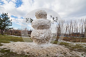 Huge spring snowman in melted meadow. Background with copy space for lettering or text