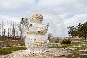 Huge spring snowman in melted meadow. Background with copy space for lettering or text