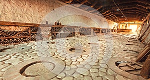 Huge stone cellar with aged wine bottles and qvevri, large earthenware vessels under ground. Rural storage of winery.