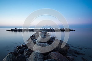 Huge stones on the beach with clear water, at susnet