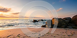 huge stones on the sandy beach at sunrise