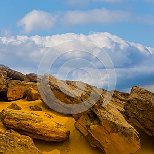 huge stones on sandy hill under blue cloudy sky