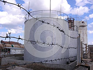 Huge tanks tanks tanks tanks for backup aviation fuel oil refining stored behind barbed wire guarded