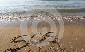 Big text SOS on the sand of the beach