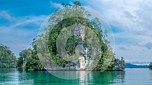 Huge Triangle Rock overgrown with Palmtrees in Hidden Bay on Gam Island near Kabui and Passage. West Papuan, Raja Ampat, Indonesia