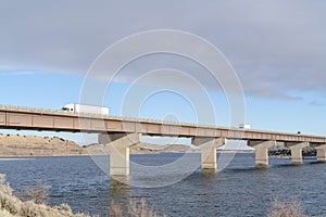 Huge trucks travelling on a massive bridge against snowy hills and cloudy sky