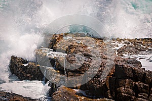 Huge wave crashing rocky coastline in Hermanus, South Africa