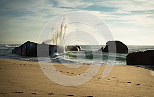 Huge wave water splash behind blockhouse on scenic beautiful sandy beach seascape with splashing waves