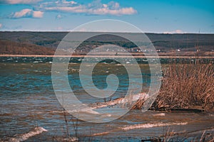 Huge waves caused by the wind on a large lake near the forest. reed beach at a dam for hydroelectric power in spring