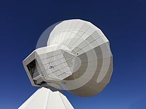 Huge white antenna radio telescope on blue sky background on top of the mountain