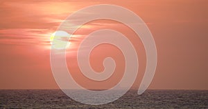 A huge white disk of the rising sun against the background of the sky and clouds painted in red and orange colors. Cargo