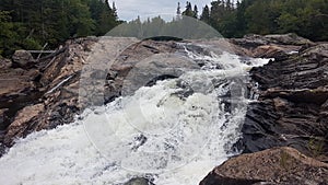 Huge white waterfall rushes down a rocky hillside