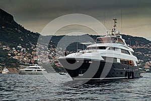 The huge yacht in sea at sunset, glossy dark board of the motor boat, the chrome plated handrail, moored mega yacht