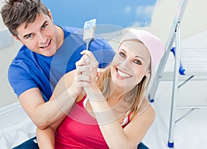 Hugging couple having fun while painting a room