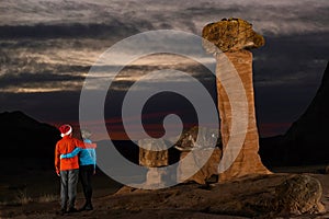 Hugging couple standing by the  giant toadstools watching sunset.