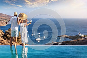 A hugging couple on vacation time enjoys the summer sunset over the Aegean Sea