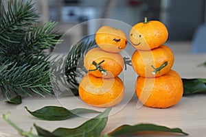 Hugging Snowman family made from tangerines on wooden table.