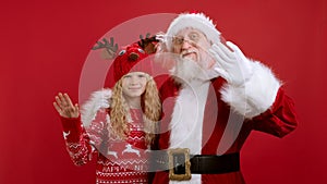 Hugs and Friendship of Santa and Child During Christmas Holidays. Cute Santa Claus in Red Outfit Hugs Little Blonde Girl