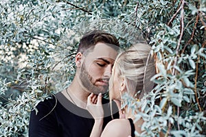 Hugs and kiss loving couple in the branches of the bushes. Walk along the road, a man kissing a woman. Love affection relationship