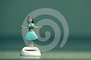 A hula dancer bobble figure on isolated green grey background, this toy is solar powered and dances all day long
