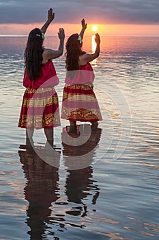 Hula dancers in ocean at sunset
