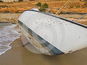 The hull of a sailboat thrown by a storm on the shore of the sea photo
