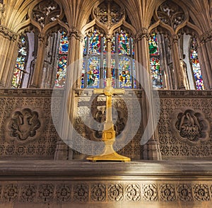 HULL, UK - 3RD MARCH 2019: A yellow painted crucifix sits in front of stained glass in the Hull Minster