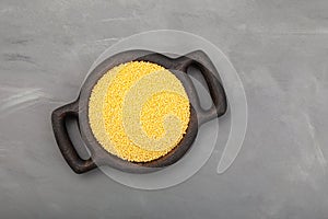 Hulled millet in wooden tray, top view. Yellow grain, top view. Grey background, copy space photo