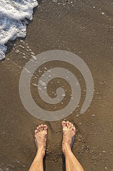 Human barefoot feet in wet sand on sea shore, active healthy living concept