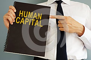 Human Capital concept. Manager holding book.