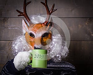 Human in a deer mask drinking green tea, on a rough wooden back