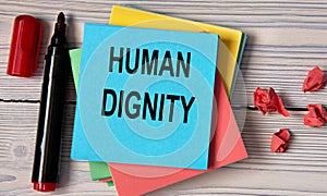 HUMAN DIGNITY - words on a note sheet on a wooden light background